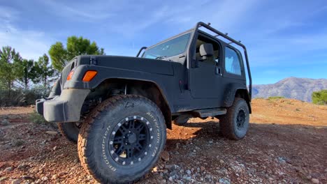 Black-Jeep-4x4-car-on-a-sunny-day-on-Sierra-Bermeja-mountain-top-with-green-trees,-fun-ATV-adventures-in-Marbella-Malaga-Spain,-4K-shot