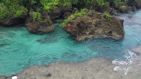 Magpupungko-tidal-rock-pools-with-people-jumping-and-swimming-in-clear-blue-water