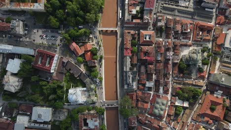 Drone-view-of-the-rich-Bosnian-city-where-cultural-heritages-live-together,-aerial-shot-of-the-river-passing-through-the-middle-of-the-city