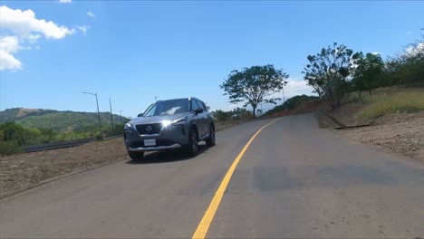 Nissan-X-Trail-Conduciendo-Por-La-Calle-Entre-árboles,-Calle-De-Grava,-SUV-Crossover-Compacto