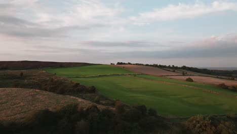 Drone-footage-over-fields-and-countryside-with-trees-and-cloudy-summer-sky