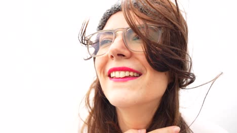 Cute-woman-with-glasses-and-messy-hair-smiling-at-camera-on-windy-day