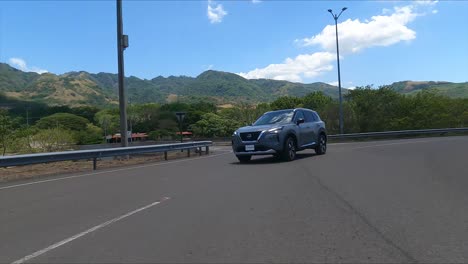 Nissan-X-Trail-Conduciendo-En-La-Calle-Entre-árboles,-SUV-Crossover-Compacto-De-Calle-De-Grava