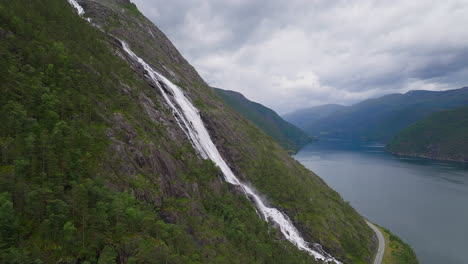 Cascading-white-water-from-Langefoss-waterfall-drips-down-steep-alpine-cliff-into-fjord-below