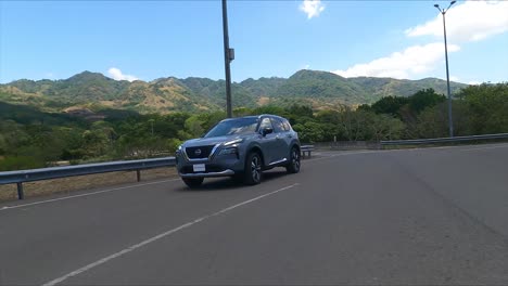 Calle-De-Grava,-Nissan-X-Trail-Conduciendo-Por-La-Calle-Entre-árboles,-SUV-Crossover-Compacto