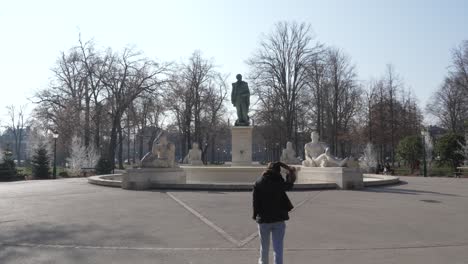 Female-tourist-walking-around-square-with-the-Monument-Bartholdi-statue-fountain-in-the-background