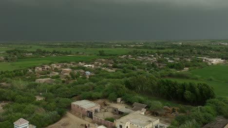 Aerial-pan-shot-of-a-lush-village-near-Mirpur-Khas,-Sindh,-under-stormy-skies
