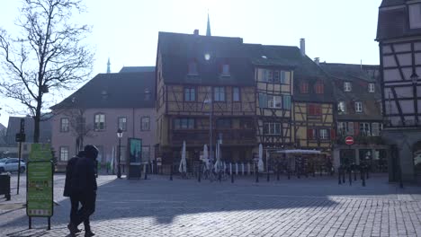 People-walking-on-pedestrian-cobblestone-square-with-traditional-half-timbered-medieval-and-early-Renaissance-buildings