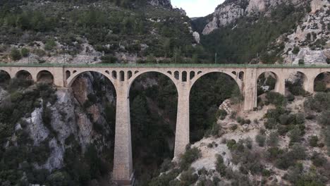 Drone-shot-of-the-big-bridge-built-over-the-canyon,-aerial-view-of-an-old-historical-bridge