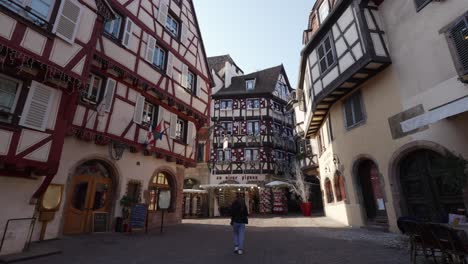 Female-tourist-walking-around-empty-streets-of-medieval-town-in-France-with-half-timbered-building-streets