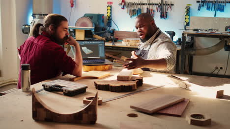 Woodworkers-designing-custom-3D-furniture-on-notebook-in-studio