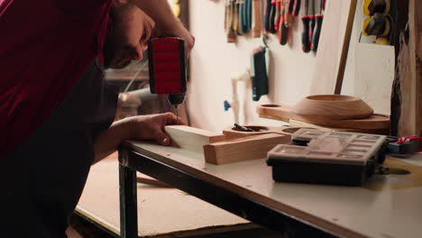 Cabinetmaker-drills-hole-into-lumber-block,-doing-furniture-assembling