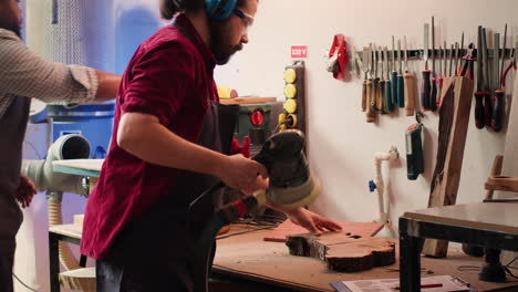Artisan-with-protecting-equipment-uses-angle-grinder-on-wood