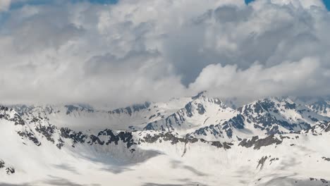 Air-flight-through-mountain-clouds-over-beautiful-snow-capped-peaks-of-mountains-and-glaciers.