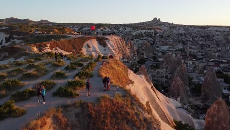 Luftaufnahme-Der-Berühmten-Felsformationen-Kappadokiens-Mit-Touristen-überall-Und-Der-Türkischen-Roten-Flagge