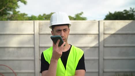 An-Engineer-in-a-White-Hard-Hat-is-Conversing-with-Another-Person-Over-the-Phone---Medium-Close-Up