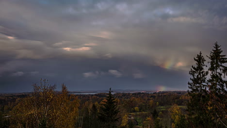 Time-lapse-moving-clouds,-rainbow-in-the-sky-in-countryside-forest-of-Riga,-Latvia