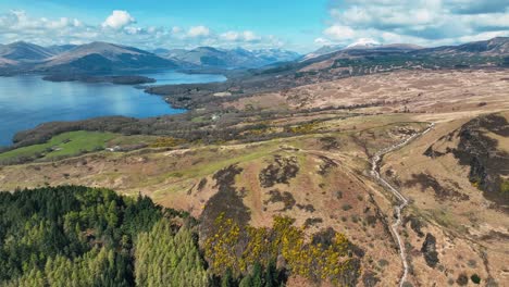 Aerial-View-of-Loch-Lomond-and-Surrounding-Mountains,-Views-of-Scotland,-Conic-Hill-on-a-Blue-Sky-Spring-Day-in-Scottish-Highlands,-Scotland