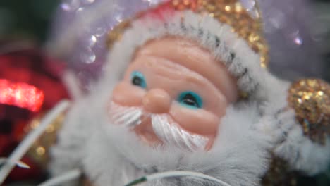 X-mas-golden-plastic-Santa-Claus,-big-white-beard,-blue-eyes,-Christmas-decoration,-traditional-holiday-new-year-decor,-shiny-colorful-setup,-cinematic-slow-macro-tilt-up-shot,-4K-video
