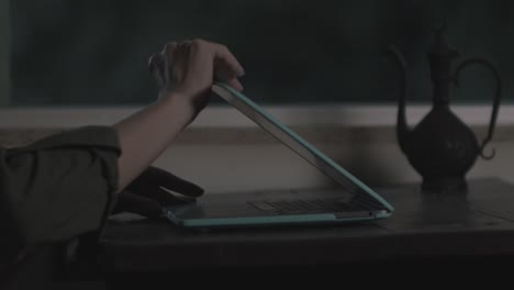 Feminine,-delicate-hands-open-and-type-on-a-laptop-in-low-light