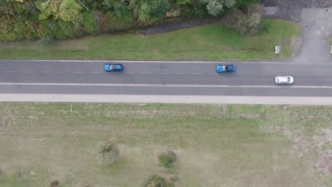 Aerial-view-of-blue-cars-drive-on-two-way-road-and-pass-by-white-car