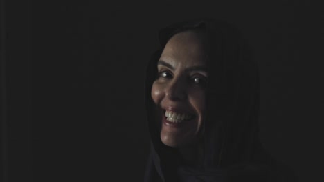 Eine-Muslimische-Frau-Blickt-Mit-Einem-Breiten-Lächeln-Aus-Der-Dunkelheit-Auf