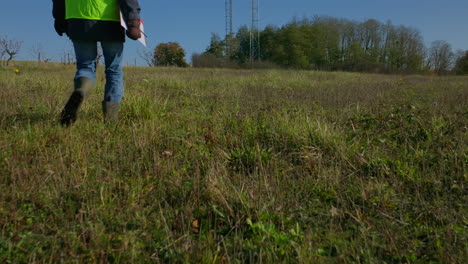 Male-engineer-walking-on-the-grass-towards-the-two-cellular-towers,-low-angle-tilting-shot-revealing
