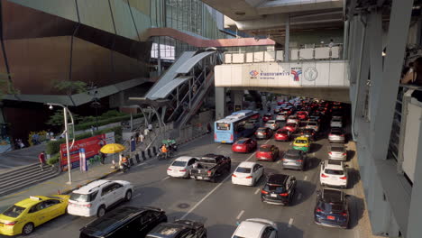 Traffic-building-up-in-front-of-a-shopping-mall-and-under-a-busy-train-station,-in-a-major-business-hub-in-Bangkok,-Thailand