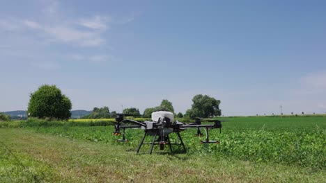 Agricultural-drone-propellers-start-spinning-and-take-off-near-green-farmland