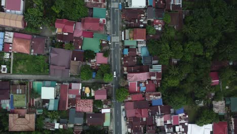 Top-down-drone-shot-of-Philippine-Provincial-Highway-with-cars,-surrounded-by-trees-and-houses