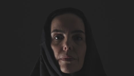 A-Muslim-woman-with-a-somber-expression-walks-from-the-darkness