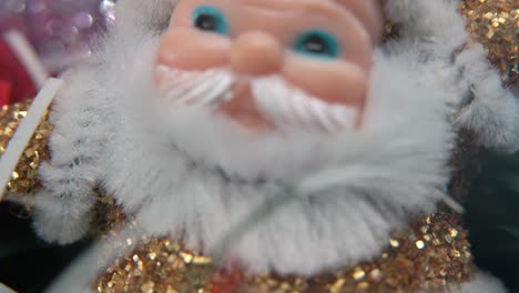 Weihnachtsweihnachtsmann-Aus-Goldenem-Plastik,-Großer-Weißer-Bart,-Blaue-Augen,-Weihnachtsdekoration,-Traditionelle-Feiertags-Neujahrsdekoration,-Glänzendes,-Farbenfrohes-Setup,-Filmische-Nahaufnahme,-Langsame-Makroaufnahme,-4K-Video