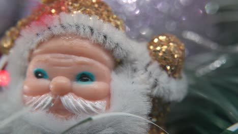 X-mas-golden-plastic-Santa-Claus,-big-white-beard,-blue-eyes,-Christmas-decoration,-traditional-holiday-new-year-decor,-shiny-colorful-setup,-creative-slow-macro-pan-right-shot,-4K-video