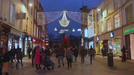 Dublin-city-shopping-street,-Christmas-decoration,-nighttime,-people-strolling