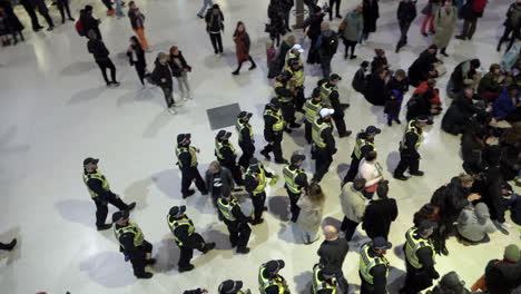 British-Transport-Police-officers-walk-into-a-group-of-pro-Palestine-sit-down-protestors-and-hand-out-notices-explaining-they-are-breaking-the-law-and-are-liable-to-arrest-at-Waterloo-train-station