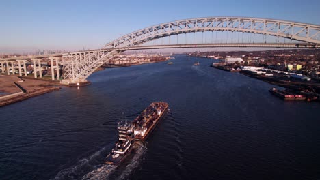 Industrial-barge-passing-Bayonne-Bridge-in-Staten-Island,-New-York