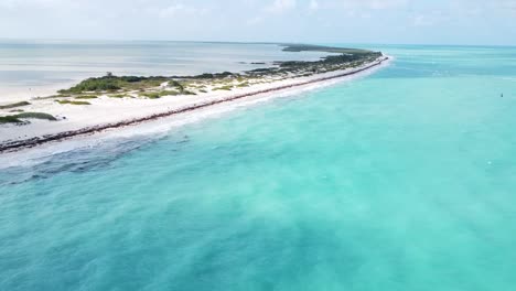 Aerial-of-Isla-Blanca,-Mexico,-view-of-picturesque-scene-where-waves-gently-crash-onto-the-pristine-white-sand-beach