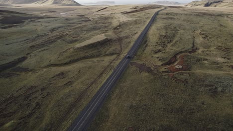 Cinematic-road-leading-through-vast-volcanic-desert-landscape,-car-driving