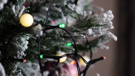 Twinkling-light-string-on-artificial-Christmas-tree-with-snow-texture