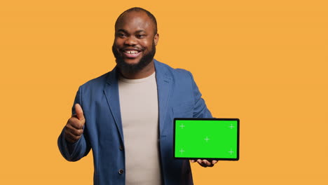 Happy-man-pointing-towards-chroma-key-device,-doing-thumbs-up-sign