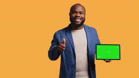 Happy-man-pointing-towards-chroma-key-device,-doing-thumbs-up-sign