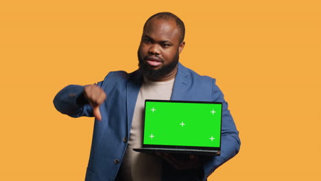 Reviewer-shows-thumbs-down-sign-gesturing-holding-green-screen-laptop