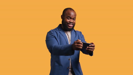 Hombre-Feliz-Jugando-Videojuegos-En-El-Teléfono-Inteligente,-Celebrando,-Fondo-De-Estudio