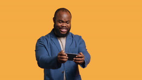 Hombre-Feliz-Jugando-Videojuegos-En-El-Teléfono-Inteligente,-Celebrando,-Fondo-De-Estudio