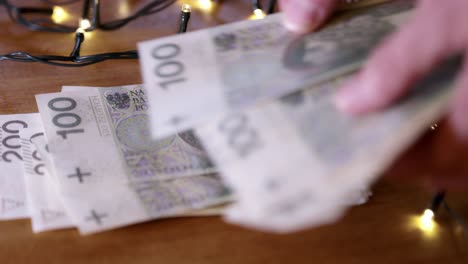 Mann-Zählt-Geld,-Polnisches-Bargeld-Als-Weihnachtsgeschenk,-Nahaufnahme,-Die-Weihnachtsbeleuchtung