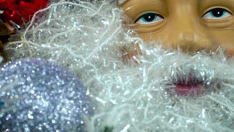 Weihnachtsmann-Gesicht-Mit-Rotem-Hut-Und-Glöckchen,-Großer-Weißer,-Glänzender-Bart,-Weihnachtsdekoration,-Traditionelle-Feiertagsgeschenke,-Neujahrsdekoration,-Farbenfrohes-Setup,-Kreative-Nahaufnahme,-4K-Video
