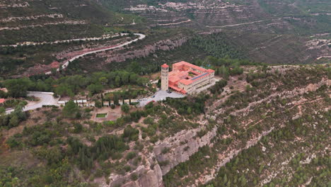 Aerial-panoramic-shot-skillfully-capturing-a-monastery-nestled-amidst-the-embrace-of-lush-green-mountains