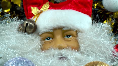 X-mas-Santa-Claus-face-in-a-red-hat-with-bells,-big-white-beard,-Christmas-decoration,-traditional-holiday-presents,-new-year-decor,-shiny-colorful-setup,-creative-close-up-tilt-up-shot,-4K-video