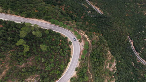 Drone-top-down-shot-expertly-following-a-car-along-a-winding-mountain-road