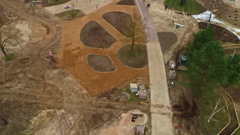 Tilting-drone-images-of-a-park-under-construction,-a-bulldozer-at-work